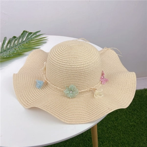 Detailed close-up of a straw sun hat featuring colorful mesh flowers and a wavy brim