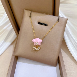 Close-up of pink flower pendant with zircons in a golden jewelry box on satin