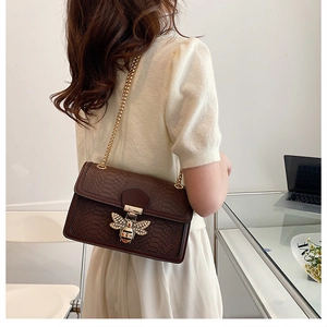 Deep brown snakeskin textured crossbody bag featuring a crystal bee buckle and gold chain