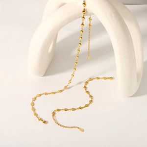 Detailed view of heart-shaped link chain with 18K gold plating on curved white display