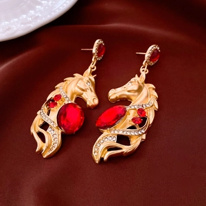 Détail de boucles d'oreilles tête de cheval vintage avec pierres rouges et strass brillants