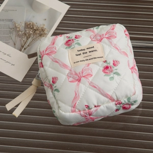 Quilted floral makeup bag with pink bows and roses pattern, featuring a zipper closure