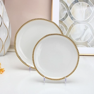 Two white ceramic plates with gold beaded edges in a stylish set for fine dining decor