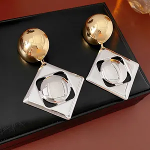 Modern gold sphere and silver square hollow earrings on black leather display case