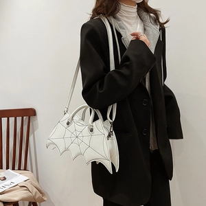 Detail of white bat-wing bag featuring black spider web stitching and skull rivets