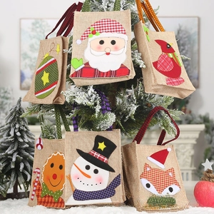 Close-up of Christmas burlap gift bags with Santa and snowman embroidery on tree