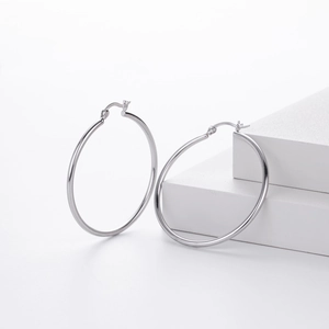 Detailed view of polished S925 sterling silver hollow hoop earrings on a geometric block