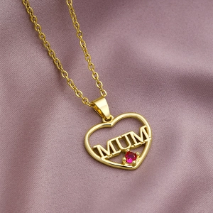 Close-up of gold heart pendant with MUM lettering and red gemstone inlay on chain