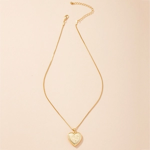 Vintage gold heart locket necklace with floral engraving and box chain on beige background