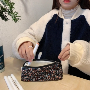 Close-up of floral canvas pencil case with multiple white markers inside for stationery storage