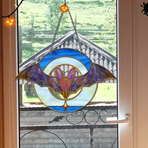 Detail of bat acrylic suncatcher with colorful patterns and metal chain hanging on window