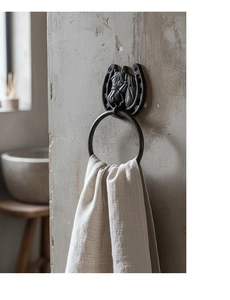 Detail of vintage cast iron horseshoe towel rack with horse head relief on rustic wall