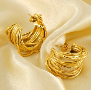 Macro detail of multi-strand twisted golden hoop earrings on elegant silk background