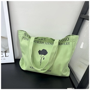 Detailed view of large canvas tote bag featuring black floral illustration and art studio text
