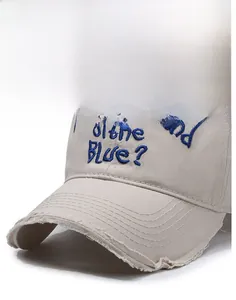 Close-up of vintage beige baseball cap featuring raw edge brim and blue 3D embroidery