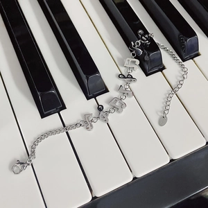 Detailed shot of musical note charms on a silver stainless steel chain over piano keys