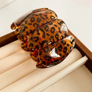 Détail du bracelet extensible en acrylique léopard dans un coffret à bijoux ambre