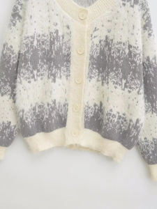 Detail view of plush faux mink knit cardigan with V-neck and cream round buttons