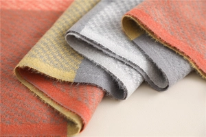 Close-up of soft plaid texture showing orange, gray, and yellow woven cashmere fabric