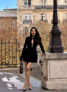 Detail of black mini dress featuring a cut-out neckline and silver metal buckle accents