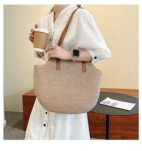 Close-up detail of large capacity straw woven tote bag with brown leather handles