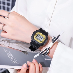 Close-up of black and gold square digital watch worn with stylish bracelets