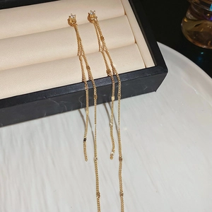Close-up of golden long tassel earrings with sparkling zircon on a luxury jewelry box