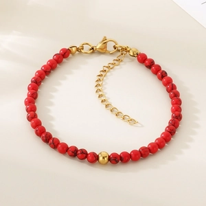 Vue détaillée des perles de pierre rouge et du fermoir doré en acier sur le bracelet