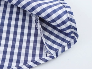 Detail of blue plaid fabric showing precise stitching and cotton texture of the dress