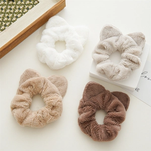 Detail view of four plush cat ear hair scrunchies in white, beige, and brown tones
