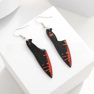Detail of bloody meat cleaver acrylic earrings with vibrant red drip patterns