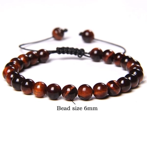 Close-up of 6mm tiger eye gemstone beads on adjustable black braided cord bracelet
