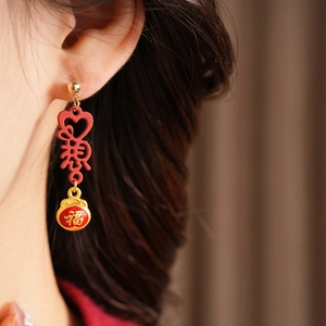 Close-up of vintage red enamel tassel earrings with gold Fu character lucky bag charms