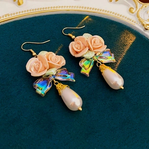 Detailed close-up of floral drop earrings with pink roses and a pearlescent teardrop bead