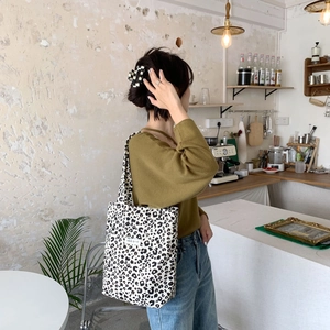 Close-up of leopard print canvas tote bag on female model in a vintage cafe setting