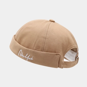 Detail showing khaki brimless cap with white New York embroidery and adjustable back strap