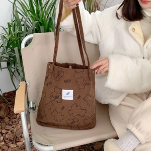 Close-up of brown corduroy tote bag with bear print and detailed fabric texture