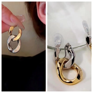Detail of two-tone chain link drop earrings with gold and silver polished metal finish