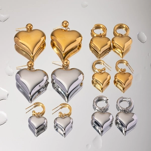 Classic gold and silver heart pendant earrings collection on a reflective mirror surface