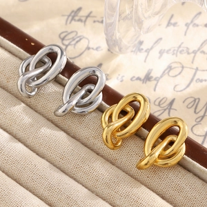 Boucles d'oreilles nœuds minimalistes en or 18K et argent sur un fond de style vintage