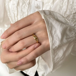 Detail shot of a minimalist gold ring with three aligned zircons on a model's hand