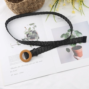 Detail of black woven belt with a round wood-texture buckle on a lifestyle background