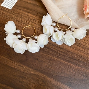 Macro view of floral tassel hoop earrings with white fabric flowers and pearls