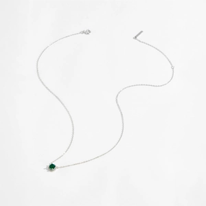 Macro detail of S925 silver necklace with green round gemstone and micro-pave crystals