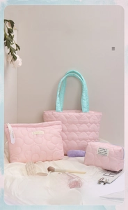 Detailed view of pink quilted storage bag set with blue handles and heart pattern embroidery