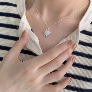 Close-up of a minimalist 925 silver starburst pendant necklace worn on neck
