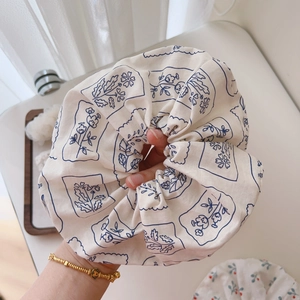 Detail of hand-held large cotton floral scrunchie with blue printed pattern