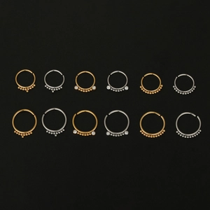 Detail of 20G surgical steel nose rings and earrings with gold and silver zircon inlay