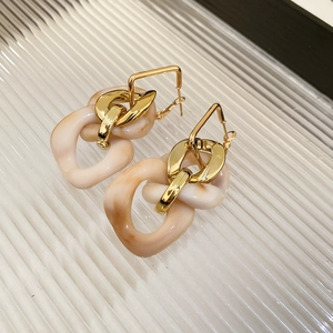 Macro detail of vintage acrylic tassel earrings with golden square hoops and marble texture