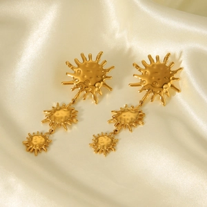 Detail of 18k gold plated stainless steel triple sun pendant earrings on beige silk